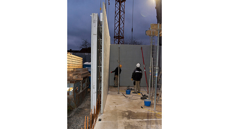 Versetzen einer Elementwand per Kran auf der Baustelle.